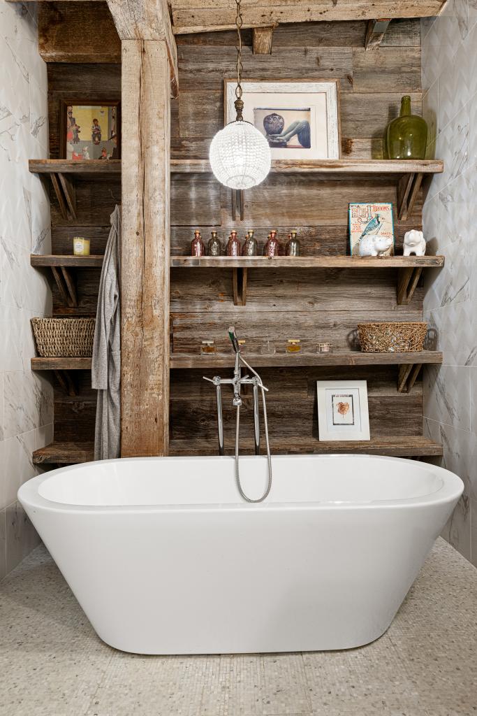 The freestanding soaking tub situated next to built-in bookshelves.