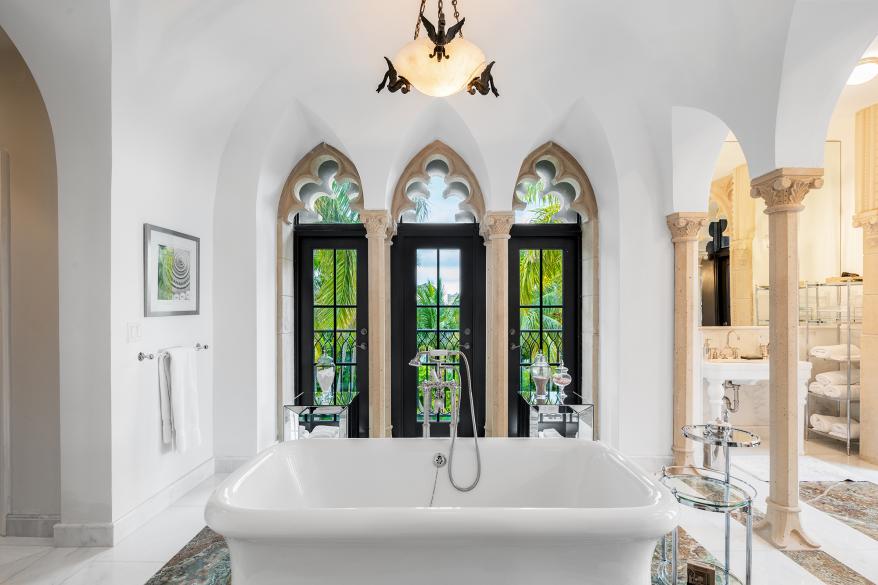 The standalone bathtub is set against three arched windows.