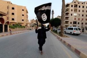 A member of ISIS waves a flag in Raqqa, Syria on June 29, 2014.