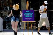 People wear protective masks as they exit a testing site for COVID-19 set up for returning students faculty and staff at NYU.