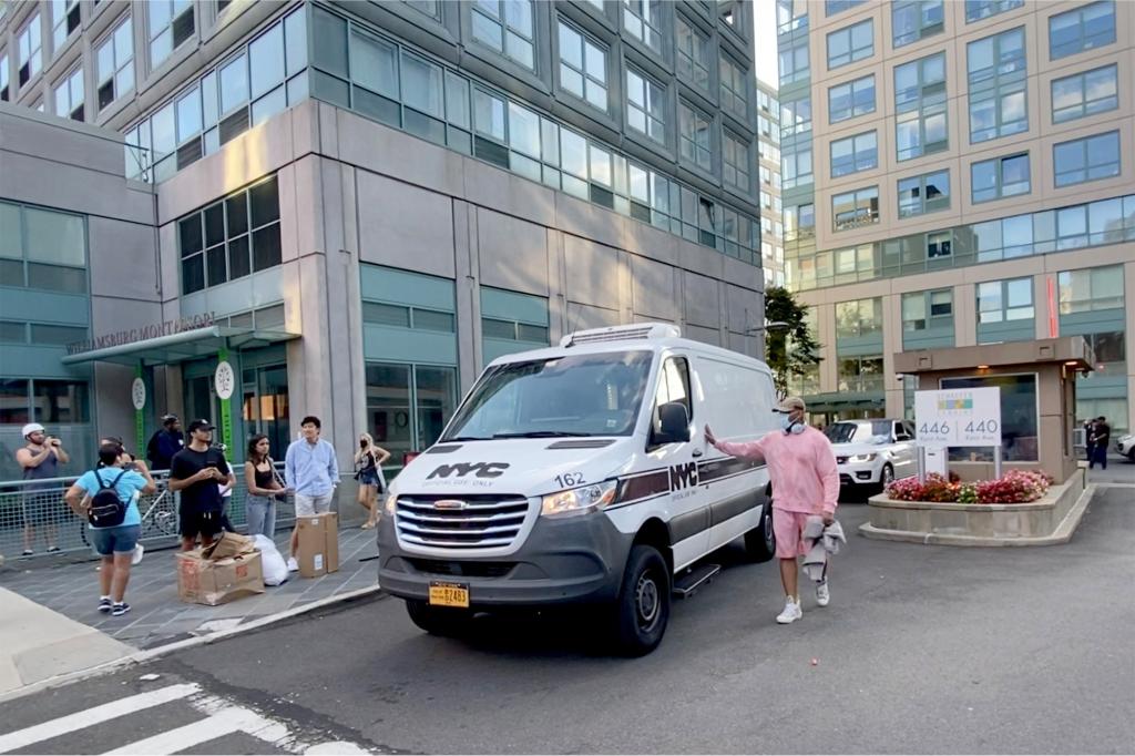 A city van carrying Williams' body away from the apartment building where he was found dead.