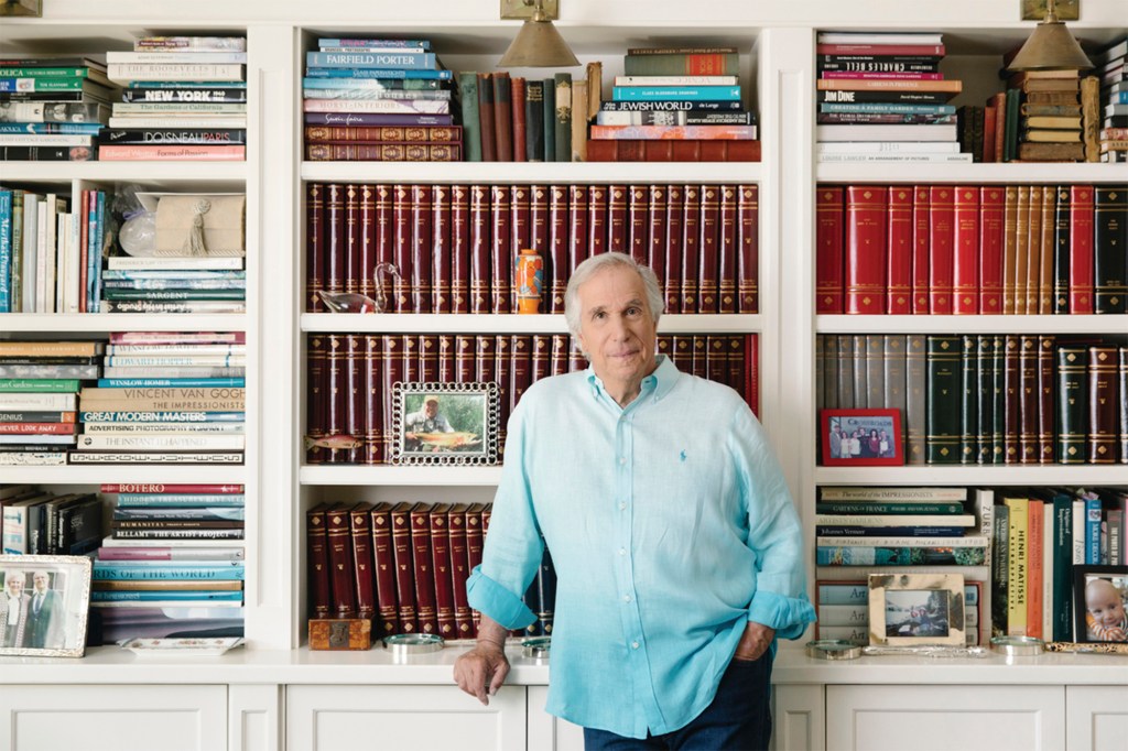 Photo showing a casually dressed Henry Winkler posing in front of a bookcase.