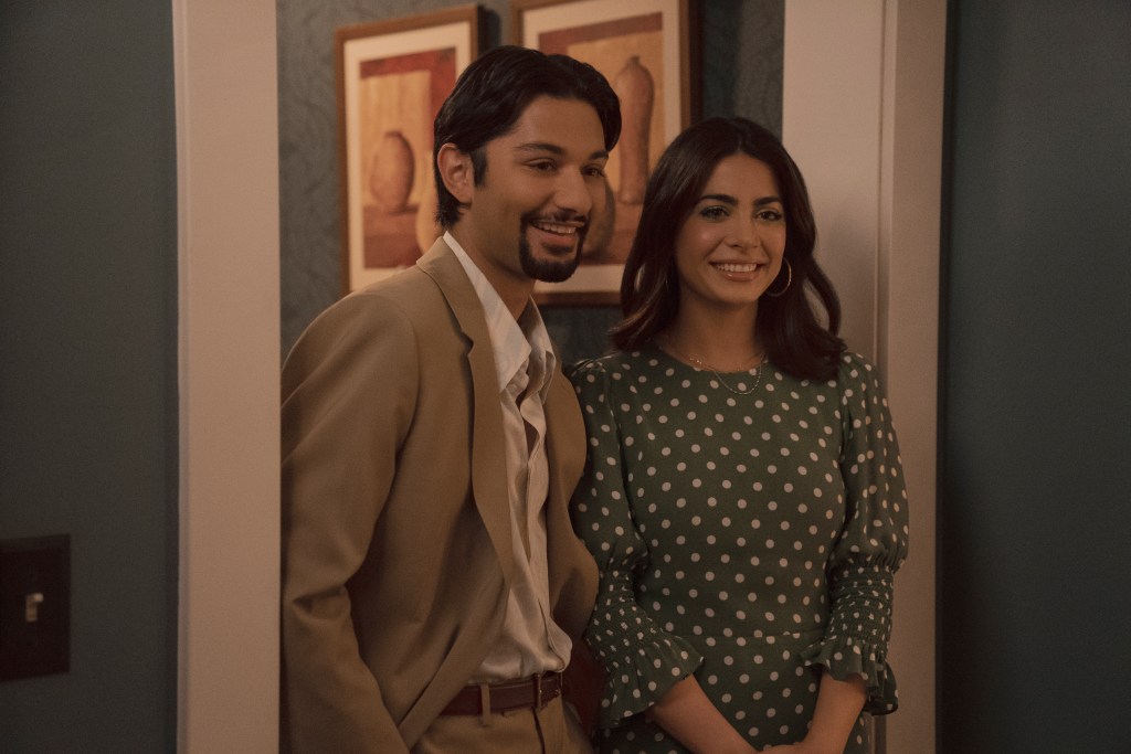 Mark Indelicato and Emeraude Toubia as Jorge Jr. and Lily in "With Love." They're smiling and standing in a doorway, looking straight ahead.