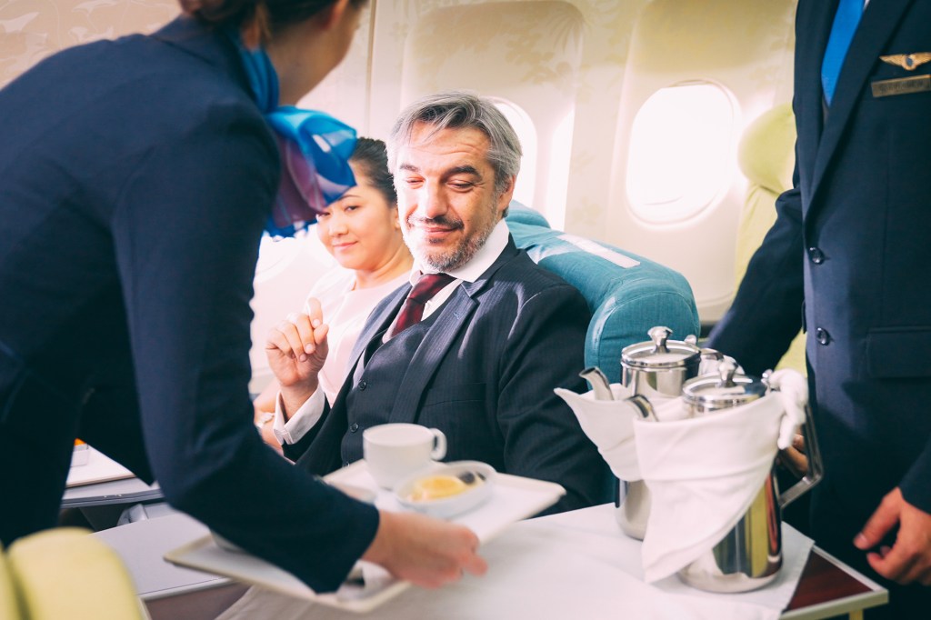 A flight crew serves passengers coffee.