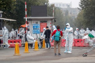 Epidemic prevention and control staff wearing protective suits stand guard at an entrance to a residential neighbourhood which is under lockdown due to new COVID-19 coronavirus cases at the Hongfuyuan residential community in Changping district of Beijing, China, 25 October 2021.