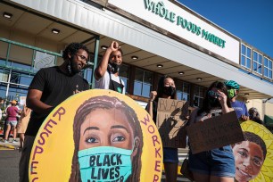 Adam Hermon, left, and Abdulai Barry stand in front of Whole Foods with other employees after getting dismissed from their shift for wearing Black Lives Matter face masks in Cambridge, MA on July 18, 2020.