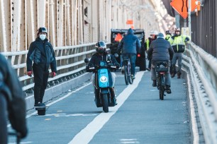 An electric scooter drives on the bike and pedestrian path over the Queensboro Bridge.