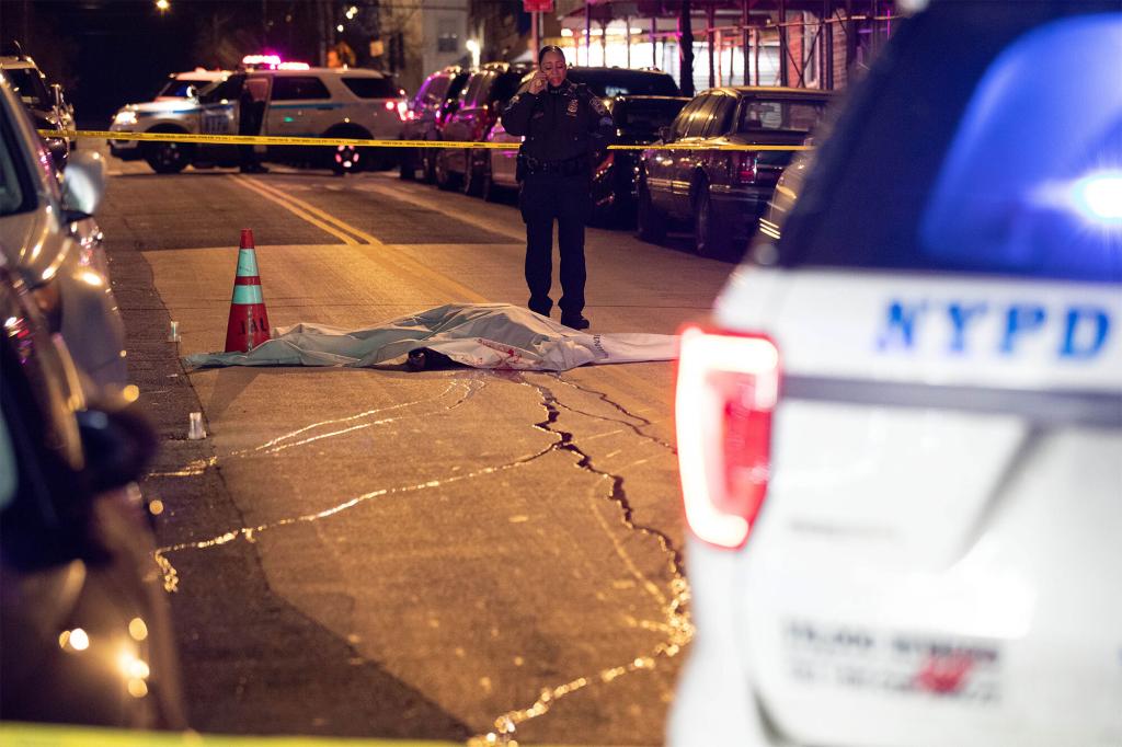 The body of a shooting victim covered with a sheet is seen lying in the street on Morris Ave. near 168th St. in The Bronx, Sunday, Dec. 26, 2021.
