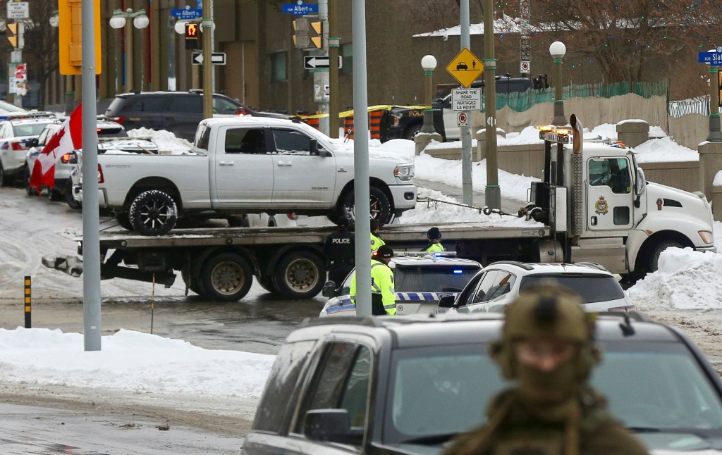 A vehicle with a Canadian flag is towed away, as Canadian police officers work to evict the last of the trucks and supporters occupying the downtown core.