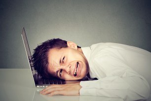 Young desperate business man with head on laptop keyboard.