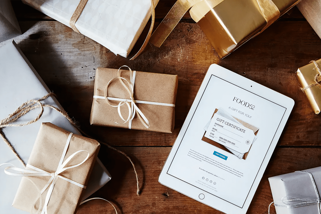 An ipad with a Food52 gift card and a bundle of presents 