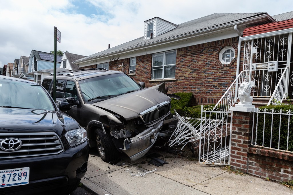 A car sits lodged onto the wall of the property at 4424 East 45th Street in Farragut, Brooklyn on Monday August 9, 2021 in New York City, USA.