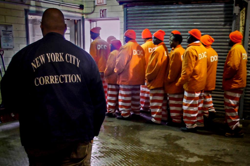 A corrections officer watches inmates exit a room.