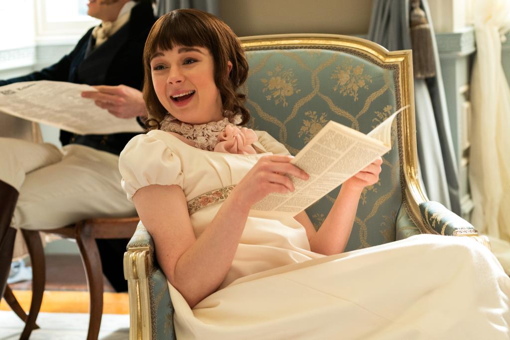 Claudia Jessie as Eloise Bridgerton reads and laughs in a white dress