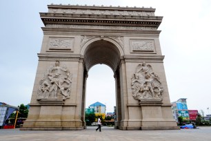A pedestrian walks past a replica of the Arc de Triomphe at the entrance of a real estate project in Jiangyan district, Taizhou city, east Chinas Jiangsu province.
