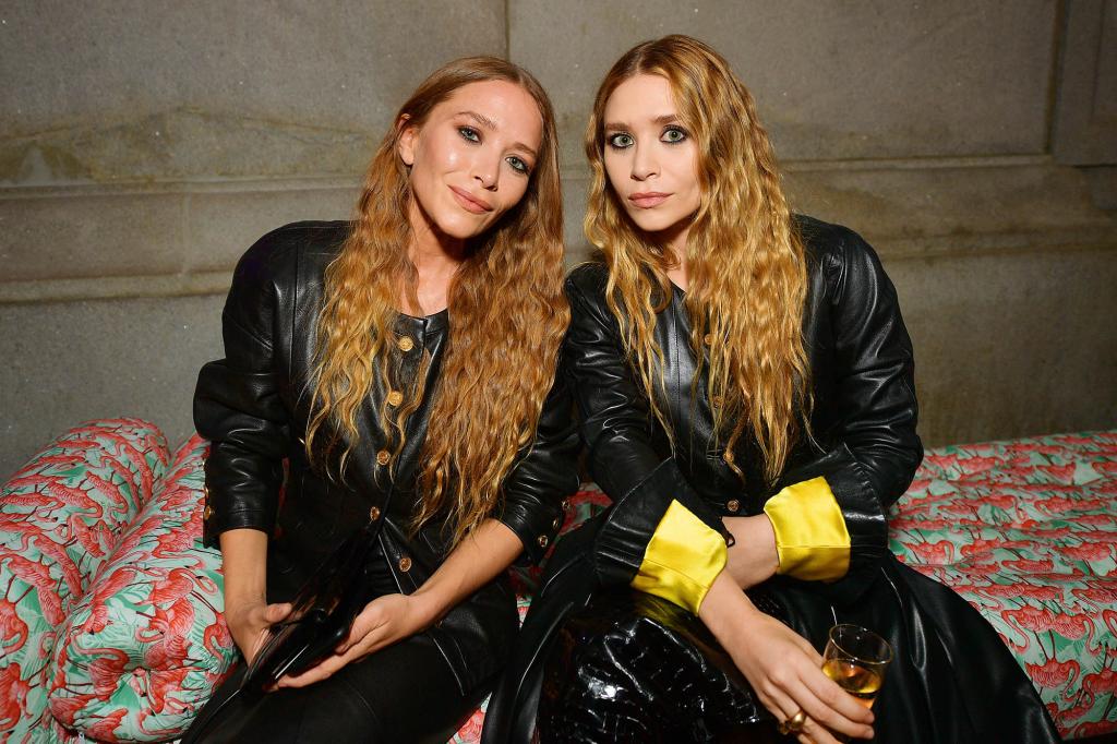The Olsen Twins pose on a flamingo couch in matching black leather