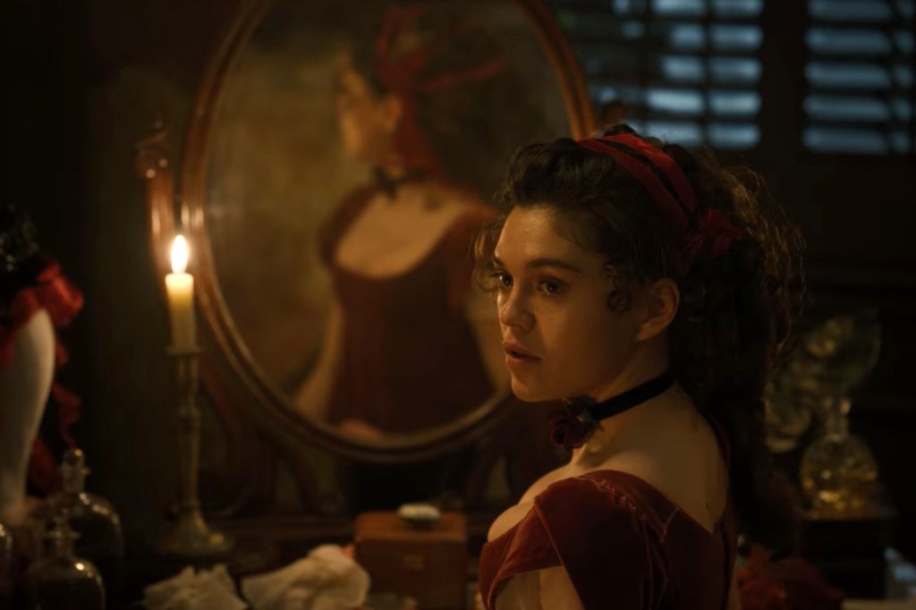 Sabrina Bartlett as Siena Rosso sits in front of a mirror in a velvet dress