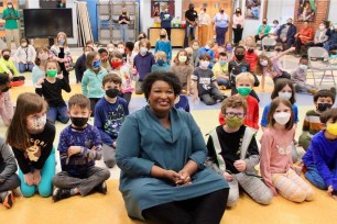 Stacey Abrams poses maskless with children who are wearing masks.
