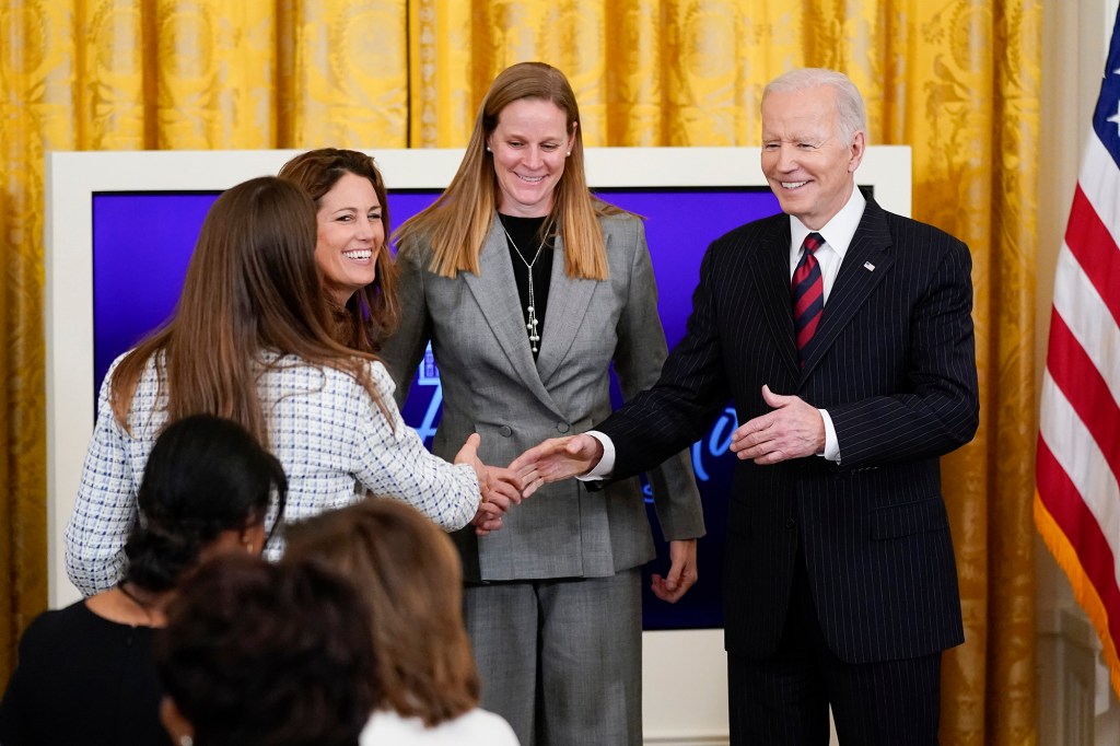 President Joe Biden shakes hands with Kelley O'Hara, member of the U.S. Women's National Team Player, left, during an event to celebrate Equal Pay Day and Women's History Month in the East Room of the White House, Tuesday, March 15, 2022, in Washington. 