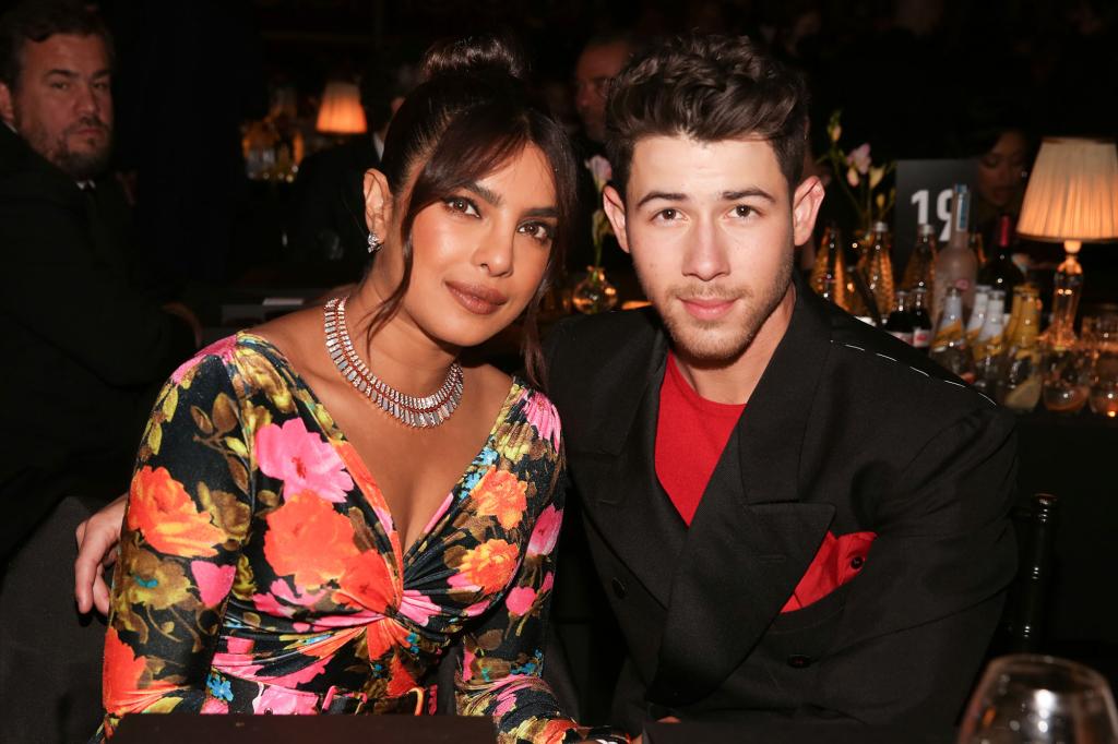 Priyanka Chopra in floral and Nick Jonas in a black suit and red shirt