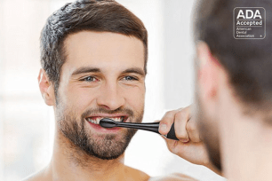 A man brushing his teeth in a mirror