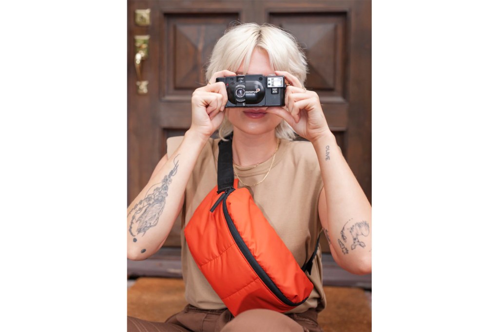 A woman with a camera and an orange crossbody bag 