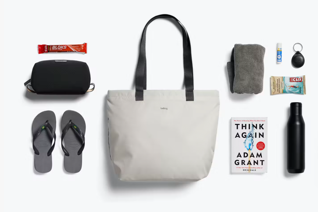 A white tote bag with an array of items around it 