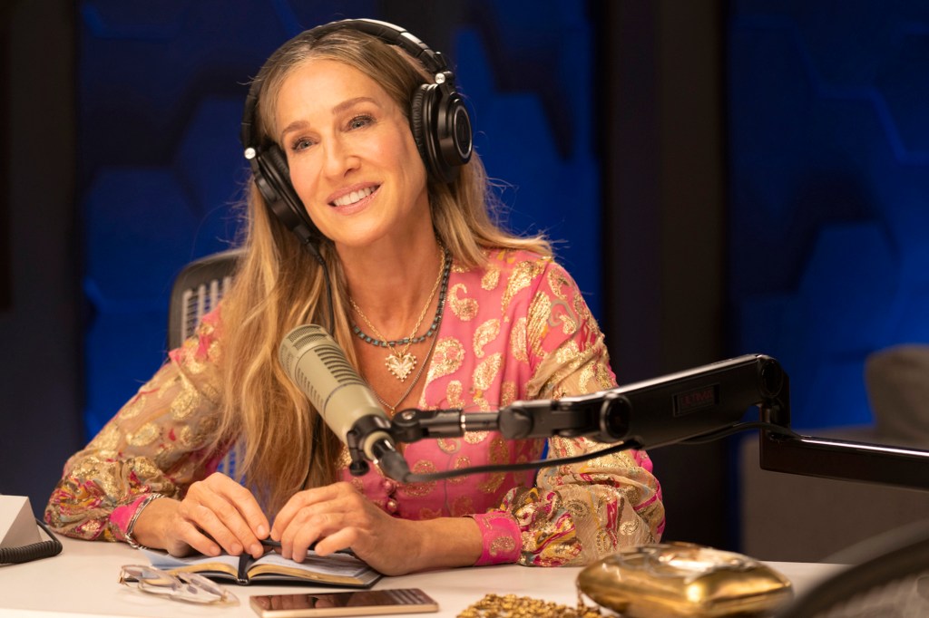 Sarah Jessica Parker smiles and wears headphones. 