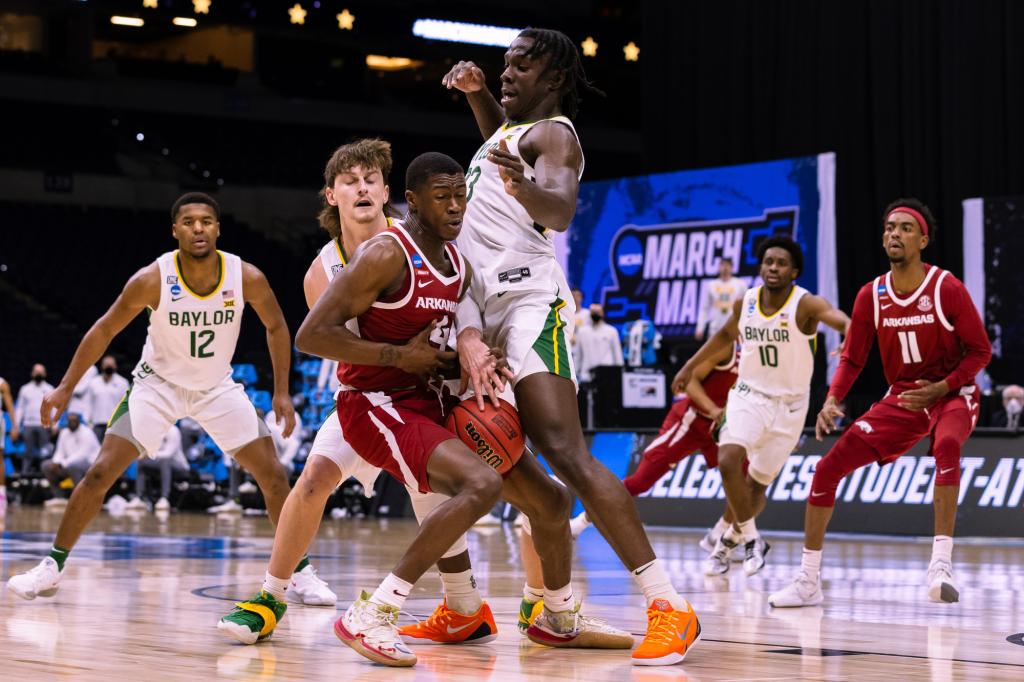 Davonte Davis #4 of the Arkansas Razorbacks loses possession of the ball while while attempting to drive past Matthew Mayer #24 and Jonathan Tchamwa Tchatchoua #23 of the Baylor Bears in the Elite Eight round of the 2021 NCAA Division I Mens Basketball Tournament.