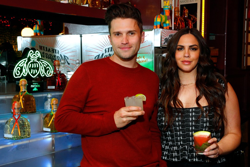 Tom Schwartz in a red shirt and Katie Maloney in a black dress hold cocktails. 