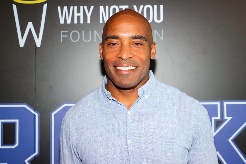 Tiki Barber smiles in a blue chambray shirt.