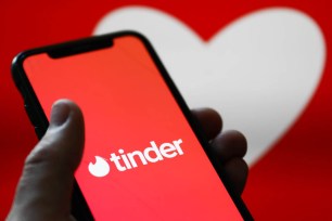 Tinder logo displayed on a phone screen and a heart shape displayed on a screen in the background are seen in this illustration photo.