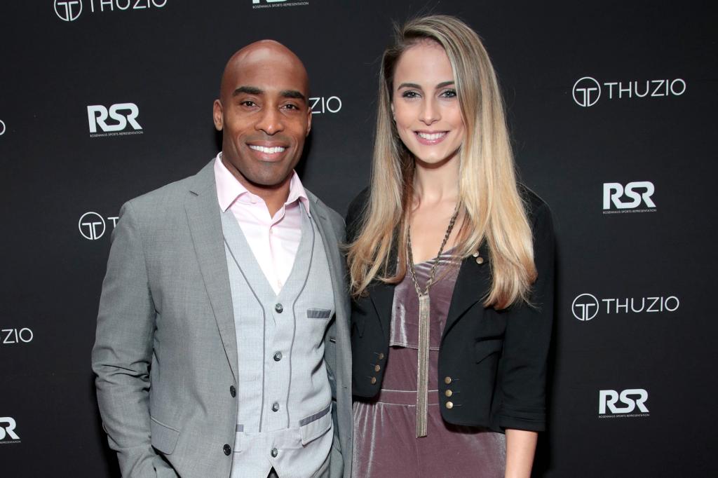 Tiki Barber in a three piece suit poses with wife Traci Lynn Johnson in a black sweater.