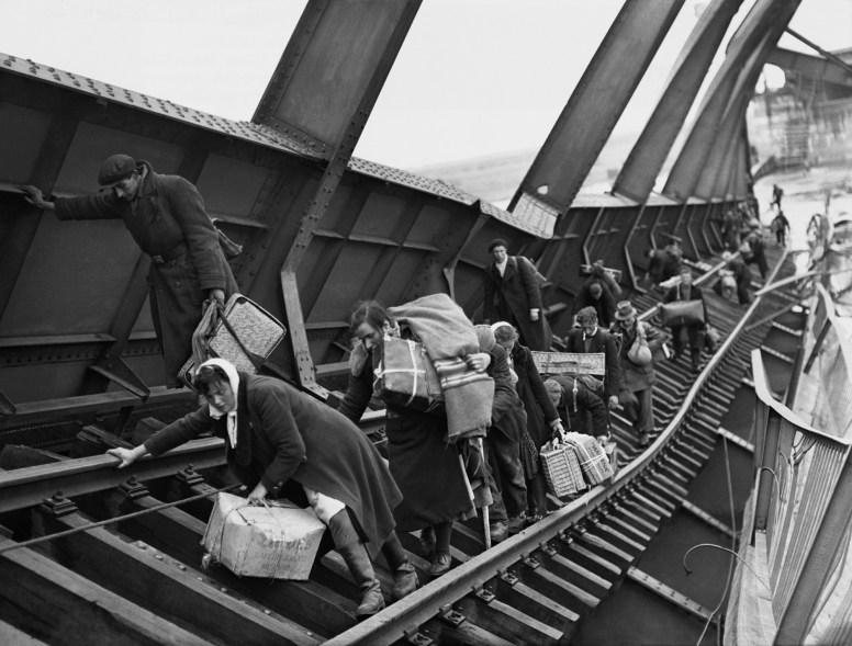 Families struggle to cross the damaged bridge at Tangermunde bombed by the Germans during World War II.