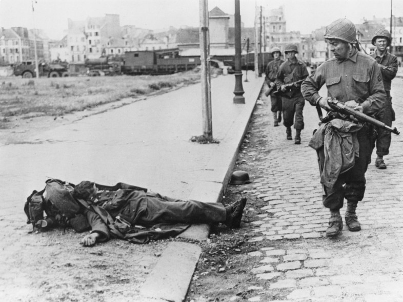 US troops liberating the French town of Cherbourg pass a dead German soldier on the pavement June 3, 1944.