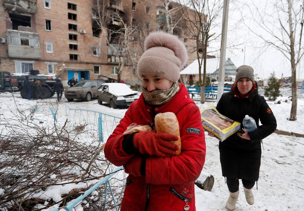 Local residents carry food and water in a residential area.