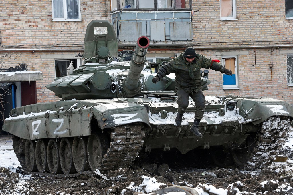 A service member of pro-Russian troops jumps off a tank.