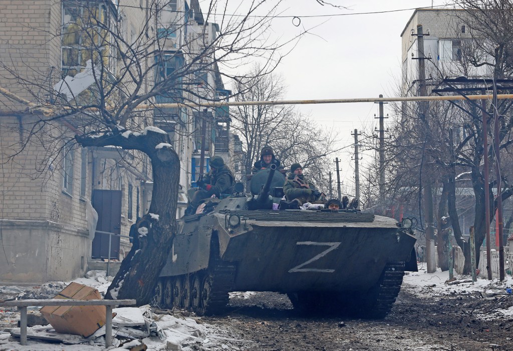 Service members of pro-Russian troops in uniforms without insignia drive an armoured vehicle with the letters "Z" painted on it in a residential area of Volnovakha.