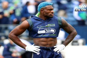 Seattle wide receiver DK Metcalf stands with his hands on his hips while wearing a sleeveless shirt with the Seahawks' logo on it.