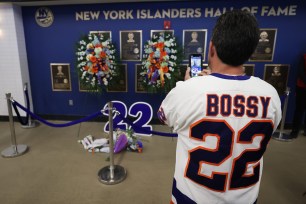 A fan stops to view the flowers surrounding the Hall of Fame plaque of former Islander Mike Bossy before their game against the Florida Panthers at UBS Arena on April 19, 2022 in Elmont, New York.