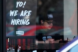 A hiring sign is displayed at a restaurant.