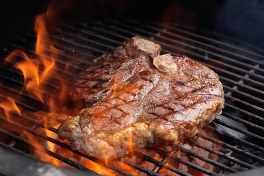 A steak cooking on a grill with fire