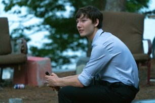 Skylar Gaertner as Jonah Byrde in the final season of "Ozark." Jonah is sitting dowon and holding a beer bottle; he's semi-smiling and wearing a blue dress shirt with the sleeves rolled up.