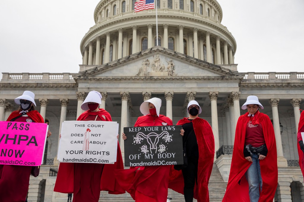 Abortion-rights protesters dressed in costumes from the "Handmaid's Tale," hold signs in front of the U.S. Capitol building.