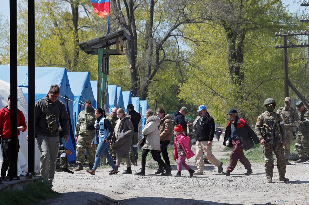 Civilians who left the area near Azovstal steel plant in Mariupol walk accompanied by UN staff at a temporary accommodation center.