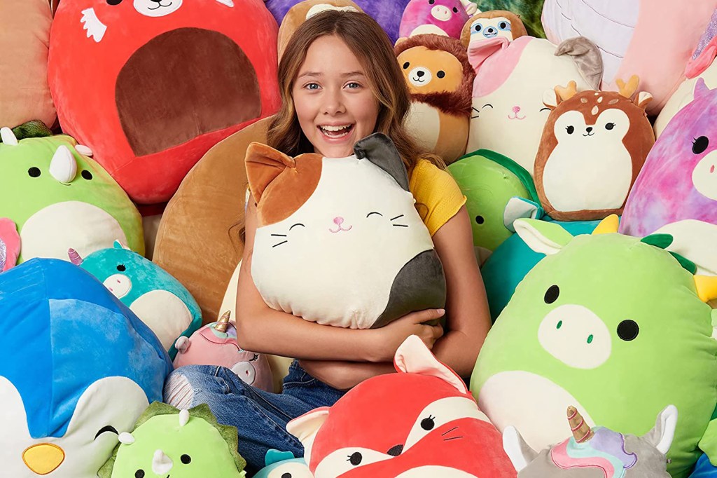 A girl in a pile of Squishmallows 