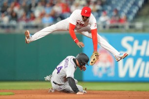 ohan Camargo #7 of the Philadelphia Phillies jumps over Ryan McMahon #24 of the Colorado Rockies