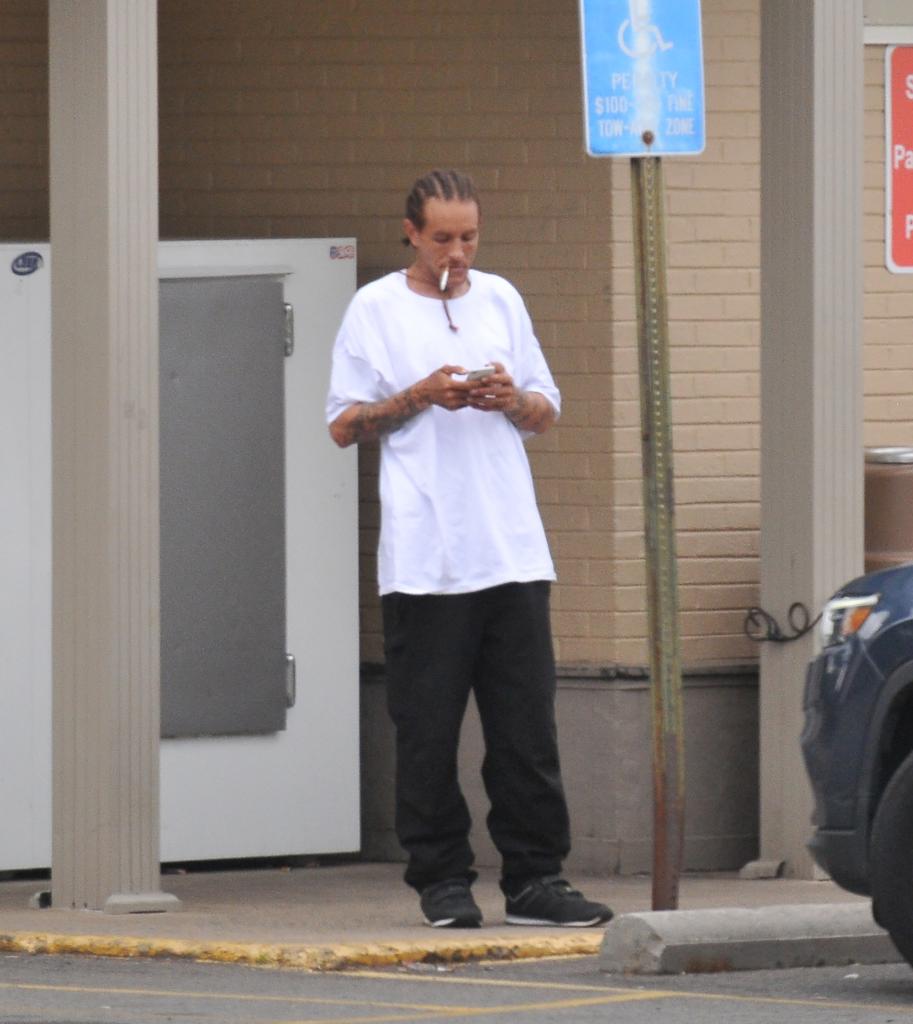 Former NBA player Delonte West smokes a cigarette and checks his cell phone outside a 7-Eleven in Alexandria, Va.