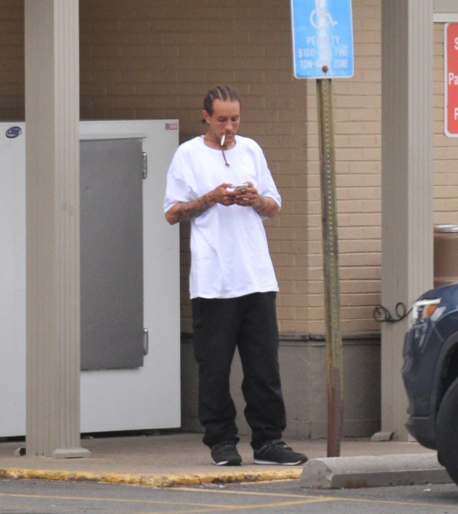 Former NBA player Delonte West smokes a cigarette and checks his cell phone outside a 7-Eleven in Alexandria, Va.