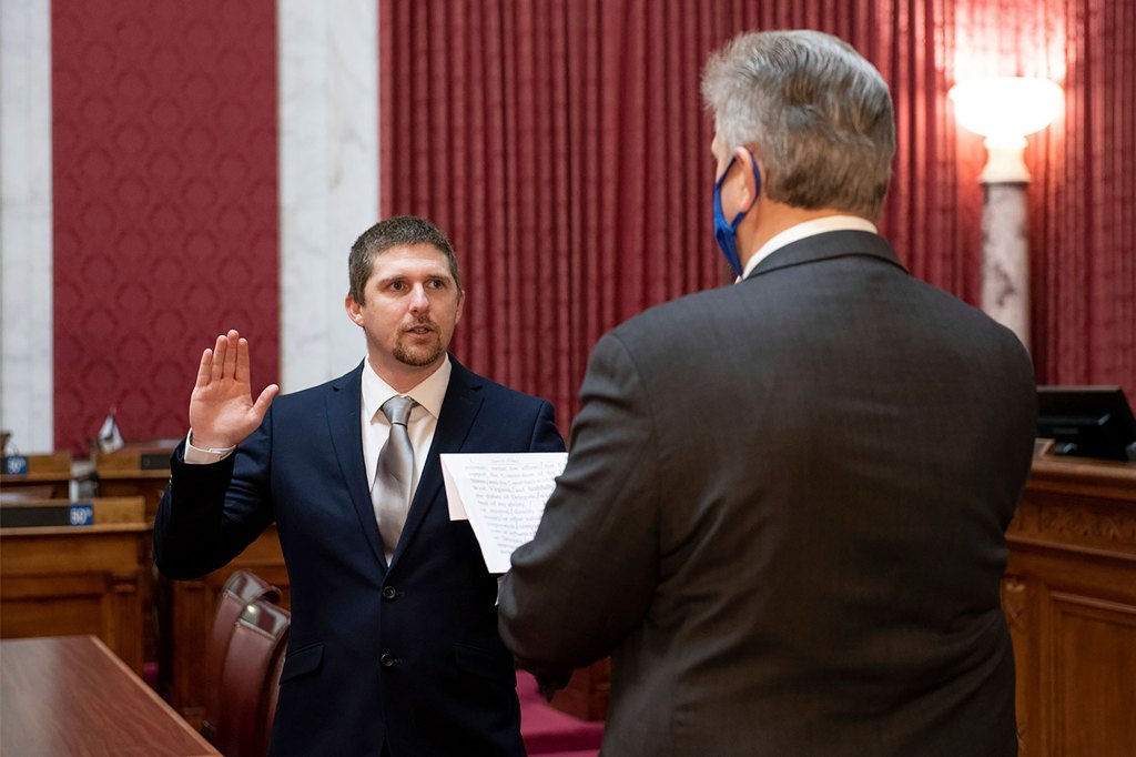 West Virginia House of Delegates member Derrick Evans, left, is given the oath of office Dec. 14, 2020, in the House chamber at the state Capitol in Charleston, W.Va. Evans recorded video of himself and fellow supporters of President Donald Trump storming the U.S. Capitol in Washington, D.C., on Wednesday, Jan. 6, 2021 prompting calls for his resignation and thousands of signatures on an online petition advocating his removal. (Perry Bennett/West Virginia Legislature via AP)